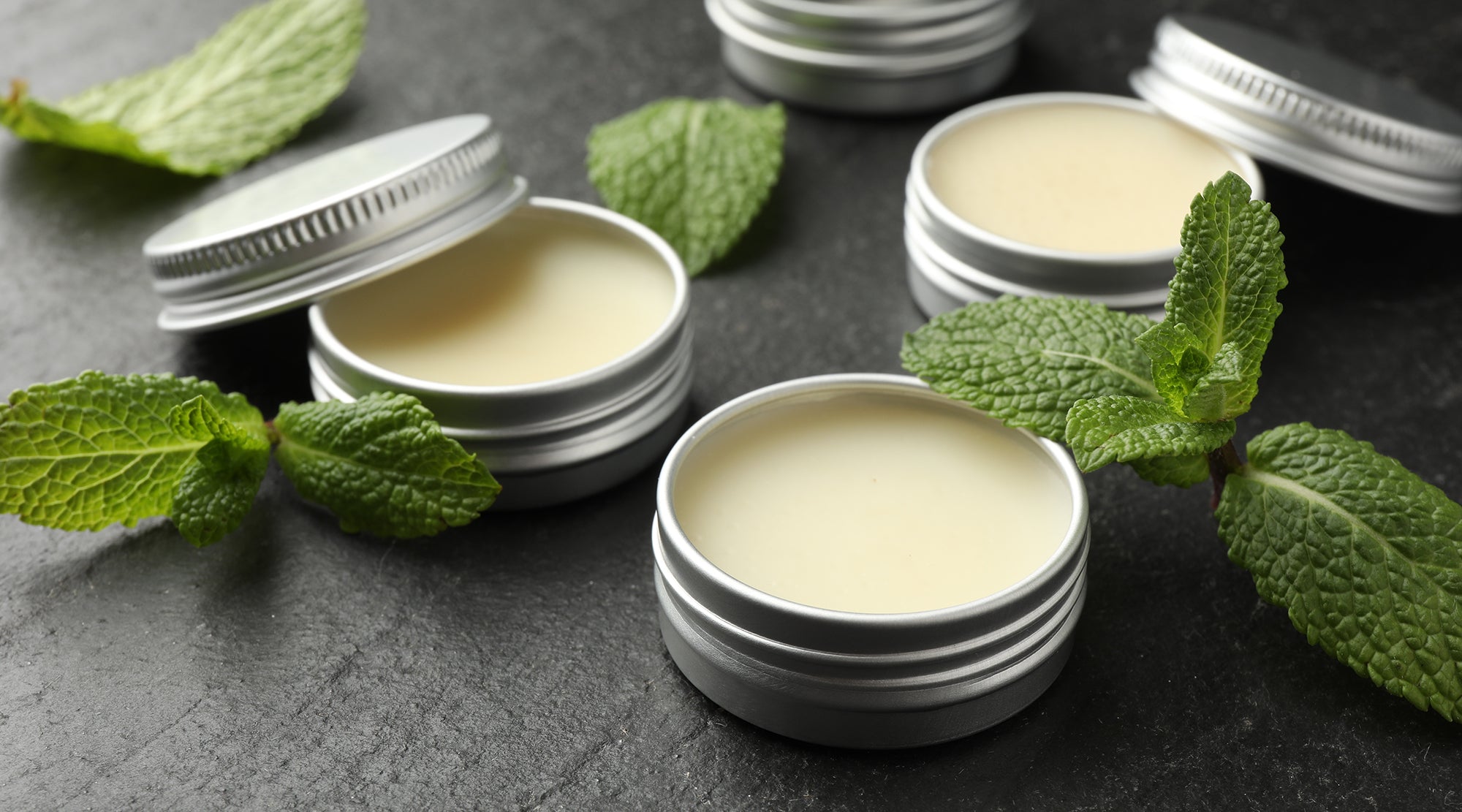 This mint skin salve is made with mint. It is sitting on a table. 